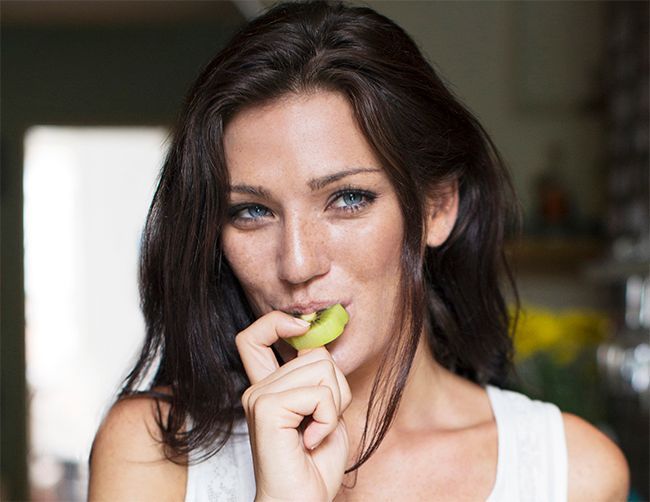 Une femme qui mange un kiwi.