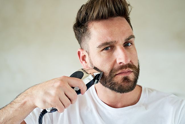 Un homme qui utilise une tondeuse sur sa barbe.